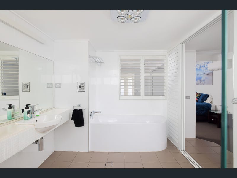 Bay room ensuite with large mirror, sink and bathtub